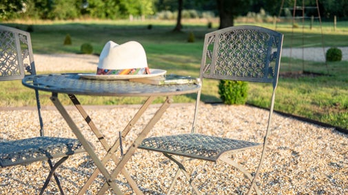 Outdoor furniture, including table and chairs with a hat placed on the table
